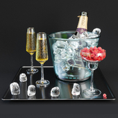 A bottle of champagne on a tray with ice and raspberries.